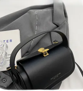 Detail of a structured black leather handbag featuring a golden shell-shaped metal clasp