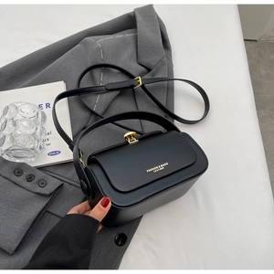 Detail of black leather crossbody bag with golden clasp and fashion logo text