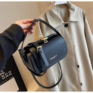 Detail of black leather cylindrical bag featuring gold hardware and white fashion lettering
