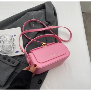 Detailed view of pink leather handbag with gold metal clasp and fashion branding