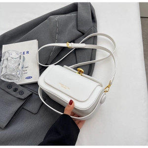 Minimalist white leather crossbody bag detail on gray suit with aesthetic props