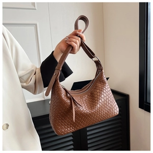 Dettaglio della trama in pelle intrecciata marrone di una borsa hobo con tracolla regolabile