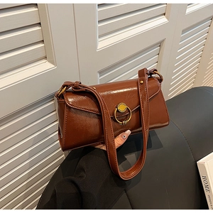 Close-up of brown oily leather shoulder bag with a prominent golden metallic buckle