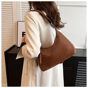Dettaglio della borsa hobo marrone intrecciata indossata da modella in blazer bianco
