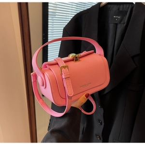 Detail of pink cylindrical crossbody bag featuring a golden seashell-shaped metal lock
