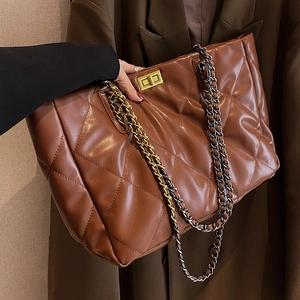 Brown quilted tote bag with gold chain strap and turn-lock closure in a close-up view