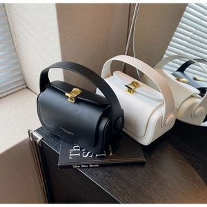 Detail of elegant black and white leather handbags with golden shell-patterned buckles