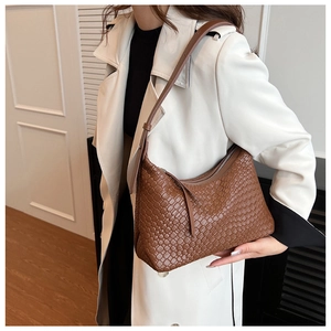 Borsa hobo intrecciata marrone indossata con cappotto bianco mostra trama e capacità