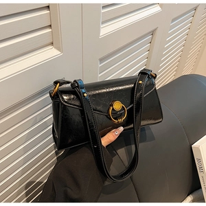 Detail of glossy black pleated shoulder bag with elegant vintage gold ring buckle
