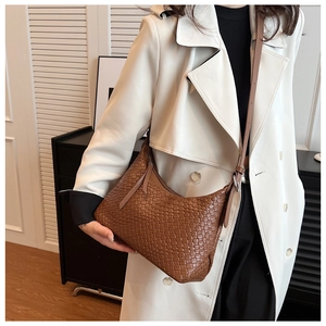 Dettaglio della trama in pelle intrecciata marrone su una borsa a mezzaluna con zip