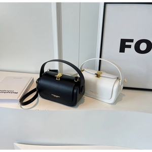Detail of black and white cylinder handbags with gold fan-shaped buckles and leather texture