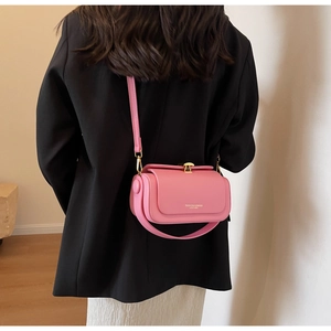 Fashionable pink crossbody bag with golden clasp worn over a black blazer by model