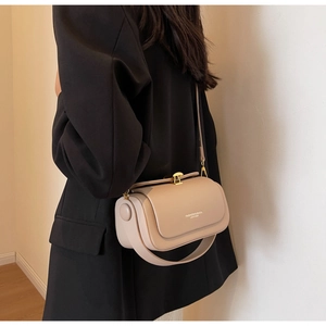 Detail of beige minimalist handbag with golden metallic clasp and smooth leather texture