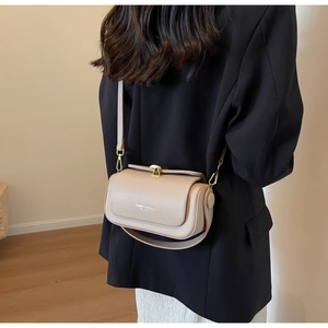 Detail of minimalist beige crossbody bag featuring gold metal lock and fashion text logo