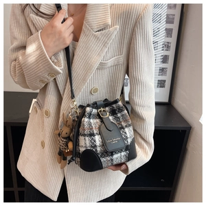 Dettaglio borsa a secchiello in tweed con patta in pelle e ciondolo a coniglio su blazer