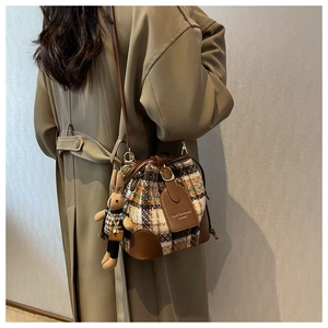 Dettaglio borsa a secchiello in tweed con patta in pelle e ciondolo a forma di coniglio