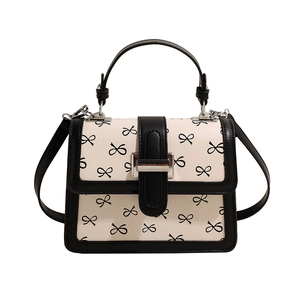Sac bandoulière blanc élégant avec motifs nœuds noirs et détail de fermoir métallique