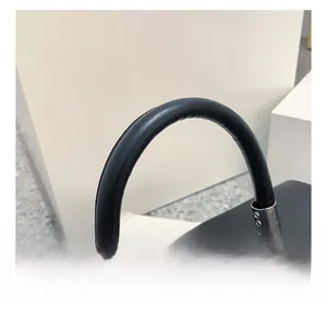 Detail shot of black leather handbag featuring round handle and matte silver buckle lock