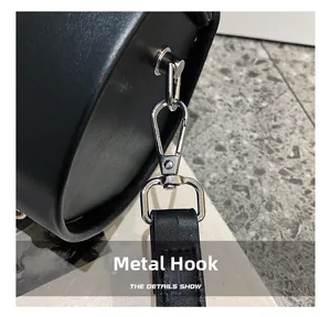 Detail of silver metal lobster clasp and hardware on a black synthetic leather bag