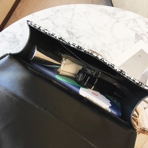 Sac bandoulière en cuir noir avec bordure en tweed et essentiels sur marbre chic