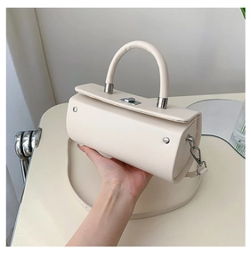 Détail d'un sac boîte cylindrique blanc crème avec fermoir argenté et bandoulière chaîne