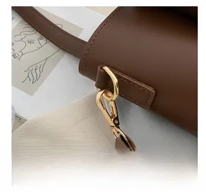 Close-up of golden metal lobster clasp and premium brown leather strap on tote bag