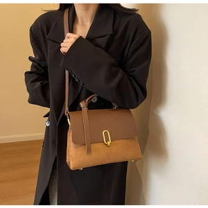 Detail of a vintage two-tone brown crossbody bag with gold buckle and smooth leather finish