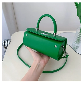 Détail d'un sac cylindrique vert vif avec fermoir en métal argenté et anse en cuir