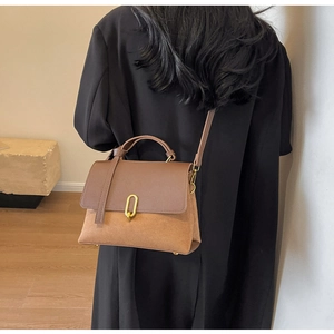 Modern two-tone leather crossbody bag with metal buckle shown on a model