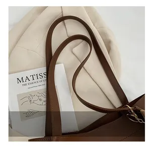 Close-up of dark brown leather tote handles with gold hardware and plush charm detail