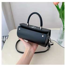 Détail d'un sac baril en cuir noir avec fermoir rotatif argenté et poignée ronde