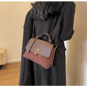 Close-up of retro burgundy suede and brown leather handbag with gold oval clasp