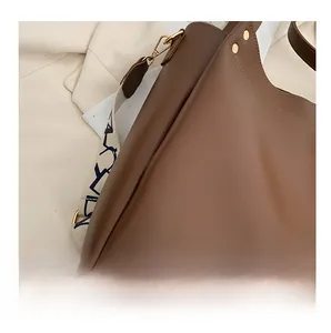 Close-up of brown leather tote featuring precise stitching and jacquard strap details