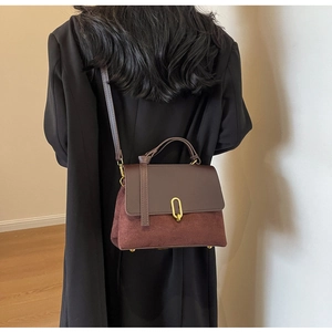 Deep burgundy leather handbag with suede patchwork and gold buckle shown on model