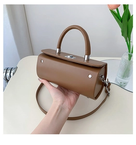Vue détaillée d'un sac à main cylindrique marron avec boucle argentée et poignée