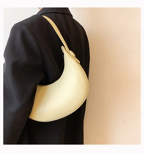 Detailed side view of cream-colored crescent underarm bag with smooth leather finish