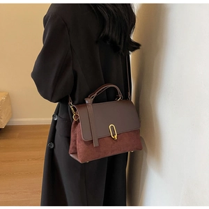 Brown and burgundy leather crossbody bag shown on model wearing black coat