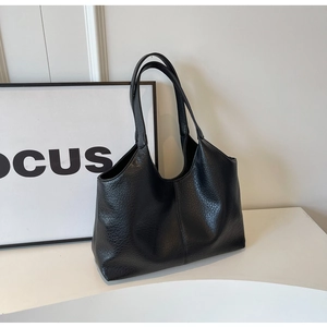 Close-up of black leather tote bag featuring refined lychee grain texture and soft straps
