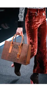 Détail d'un sac cabas marron à motif crocodile avec texture brillante et doubles anses
