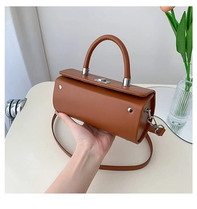 Détail macro du sac à main cylindrique marron en cuir lisse avec fermoir en métal argenté