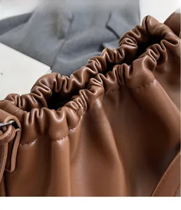 Macro shot of gathered pleated closure on soft dark brown leather shoulder bag