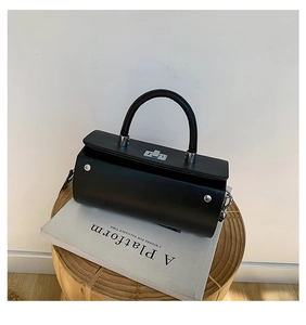 Gros plan d'un sac à main noir structuré avec fermoir rotatif argenté et rivets