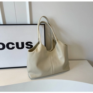 Macro detail of creamy white tote bag showing premium lychee grain leather texture