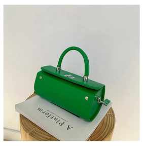 Détail d'un sac cylindrique vert vif avec fermoir argenté et poignée rigide élégante