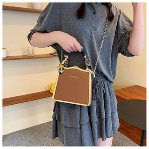 Brown structured box bag with gold metal frame and silk scarf handle detail