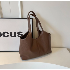 Detail shot of brown lychee grain leather tote bag showing soft texture and long straps