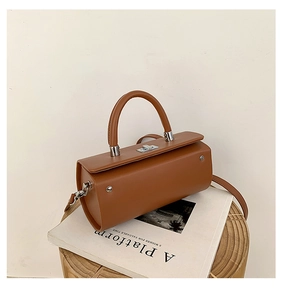 Détail d'un sac boîte en cuir marron avec fermoir métallique argenté et bandoulière