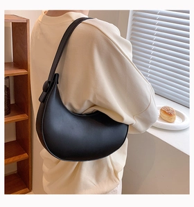 Side view of a black matte crescent underarm bag with wide strap on model back