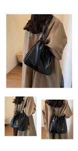 Detail showing high-capacity black drawstring hobo bag with mini & she logo and glossy texture