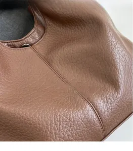 Close-up of brown lychee grain leather with neat double stitching on a tote bag detail